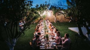Guests enjoying an elegant destination wedding dinner beneath citrus trees at Metohi Istoria, a historic Venetian estate in Chania, Crete, Greece.