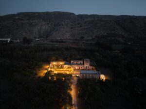 Aerial evening view of Metohi Istoria, a historic Venetian wedding venue surrounded by olive groves and the Cretan landscape near Chania, Greece.