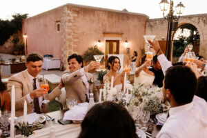 Bride and groom raising a toast with their guests during an elegant outdoor wedding reception at Metohi Istoria, a historic Venetian estate in Chania, Crete.